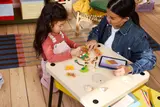 Adult and child building LEGO Moana set.