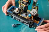 Hands revealing secret drawer in LEGO Wednesday set.