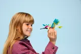 Child holding LEGO hummingbird model.