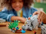 Child's hands near LEGO rhino's head during play.