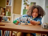 Child playing with LEGO rhino and habitat on a wooden table.