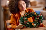 Woman holding the LEGO Holiday Wreath with red berries.