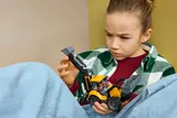 Child holding LEGO backhoe.