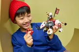 Child holding two LEGO dragons.